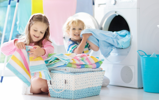 Young boy and girl enjoy benefits of a water softener in laundry room, including soft clothes.