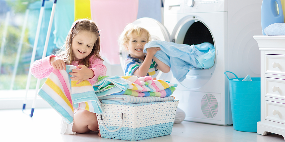 Young boy and girl enjoy benefits of a water softener in laundry room, including soft clothes.