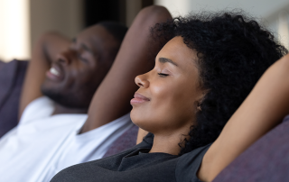 Young couple relax on couch under the comfort of zoning systems.