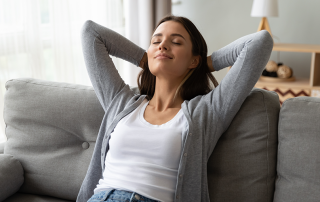 Female homeowner relaxes on couch and enjoys benefits of a humidifier