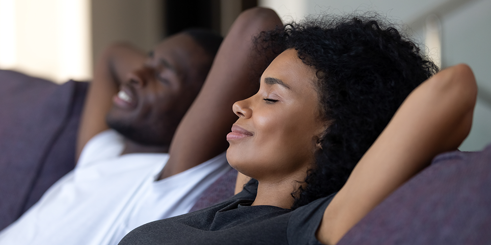 Young couple relax on couch under the comfort of zoning systems.