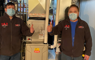 S&R techs give thumbs up near furnace after teaching homeowner how to improve air quality.