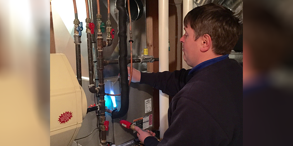 Furnace Efficiency S&R tech in dark sweater checks customer's furnace efficiency.