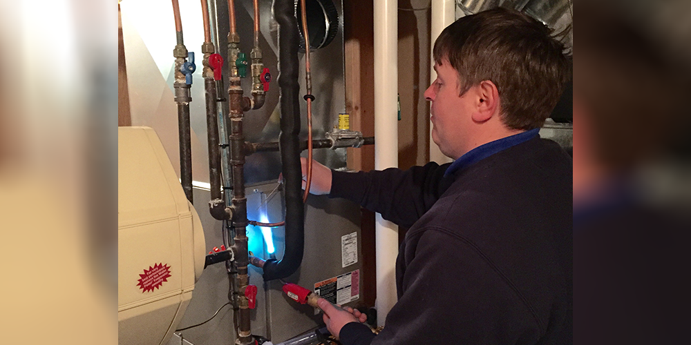 S&R tech in dark sweater checks customer's furnace efficiency.