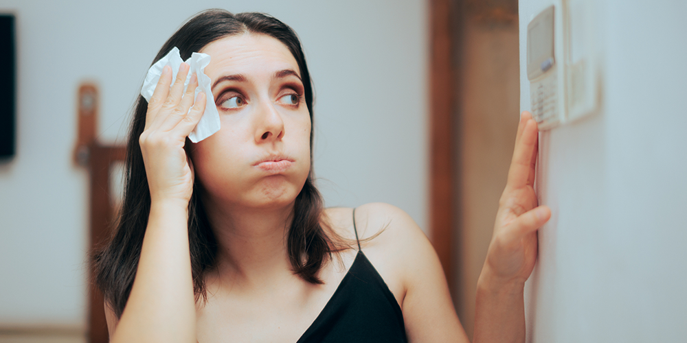 Sweaty woman whose air conditioner shuts off every few minutes adjusts thermostat.