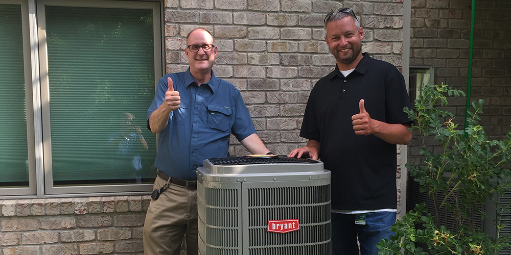 Homeowners stand next to their new house heat pump installed by S&R.