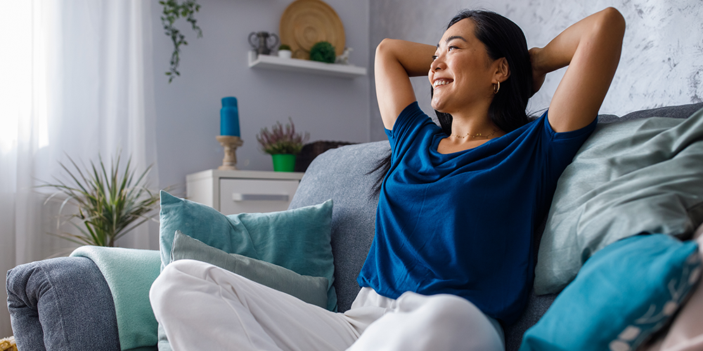 Female homeowner relaxes on couch having set ideal indoor temperature.